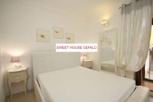 um quarto branco com uma cama e uma janela em Sweet House em Cefalù