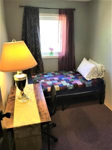 Cama en habitación con lámpara y ventana en Billie's Backpackers Hostel, en Fairbanks