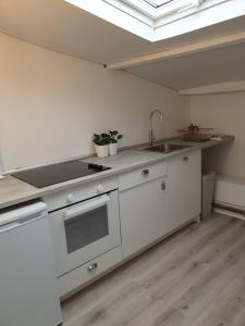 a kitchen with white cabinets and a sink and a skylight at BUHARDILLA LOFT MUY CÉNTRICA, a 50 m de MARIA PITA y del puerto in A Coruña