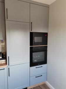 a kitchen with white cabinets and a black oven at Apartament z widokiem na Zamek in Malbork