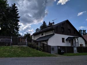 ein weißes Haus mit einem Zaun davor in der Unterkunft Haus Tolštejn in Jiřetín pod Jedlovou