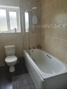 a bathroom with a tub and a toilet and a sink at No2 Glan Nodwydd in Pentraeth