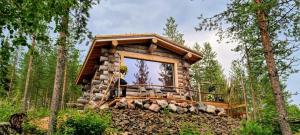 uma cabana de madeira na floresta com uma grande janela em Cozy Log Cabin by Invisible Forest Lodge em Rovaniemi