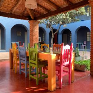 La Betulia Bed and Breakfast في مدينة أواكساكا: طاولة خشبية مع كراسي ملونة على الفناء