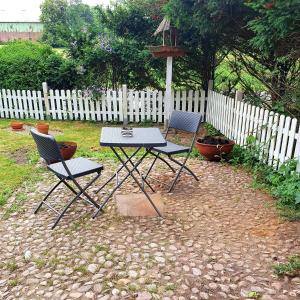 two chairs and a table in a yard with a fence at De Olle Uhlhoff in Barlt