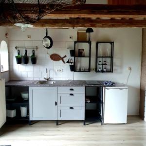 eine weiße Küche mit einer Spüle und einer Theke in der Unterkunft De Olle Uhlhoff in Barlt
