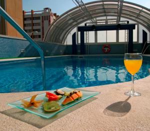 un piatto di cibo e un bicchiere di vino accanto alla piscina di Vértice Sevilla a Siviglia
