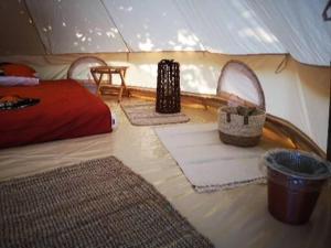 a tent with three rugs and a bed and a table at Luna Glamping in Tuzla