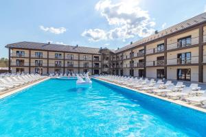 a swimming pool in front of a building with white chairs at Nikoletta in Solotvyno