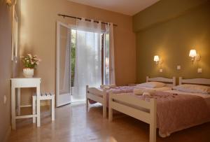 a bedroom with two beds and a large window at Maison Anna Corfu Holiday Apartments in Ýpsos