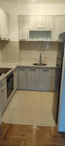 - une cuisine avec des placards blancs et un évier dans l'établissement Apartman Mateja, à Trebinje