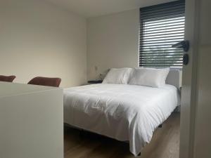 a bedroom with a bed with white sheets and a window at N9 Texel in De Koog