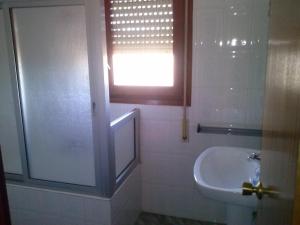 baño con lavabo y aseo y ventana en Pension Rioja, en Quinto