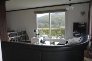 een woonkamer met een bank en een groot raam bij Heaven in Treignes