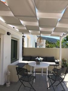 a patio with a white table and chairs at Akrogiali House in Skala Kallirachis