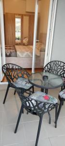 a glass table and two chairs and a table and a bed at Apartman Mateja in Trebinje