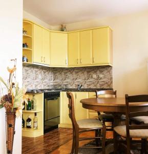 a kitchen with yellow cabinets and a table with chairs at Apartman Djina in Vrnjačka Banja