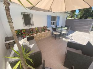 een patio met een tafel en stoelen en een parasol bij Maisonnette Cagnes in Cagnes-sur-Mer