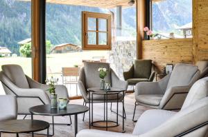 a waiting room with chairs and tables and windows at alpdeluxe-Apartments Holzgau in Holzgau