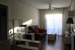 a living room with a couch and a window at ACOGEDOR APARMENTO JUNTO AL CENTRO in Huelva