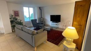 ein Wohnzimmer mit einem Sofa und einem TV in der Unterkunft Vöens, St-Blaise, Logement entier - 2 chambres in Marin