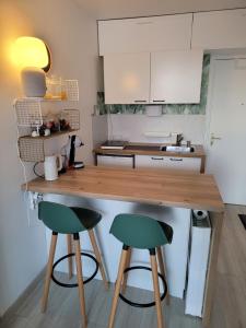 a kitchen with a wooden counter and two green bar stools at Studio bien équipé, situé en hyper centre in Vendôme