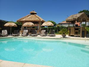 ein großer Pool mit Stühlen und Sonnenschirmen in der Unterkunft Studio Zure Ondoan - SPA et piscine chauffée in Tarnos