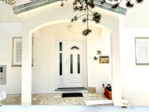 białe drzwi wejściowe białego domu w obiekcie Villa INFINITY w mieście Mandre