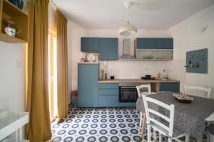 cocina con armarios azules, mesa y sillas en House L E T A, en Rukavac