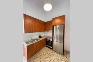 La cuisine est équipée d'armoires en bois et d'un réfrigérateur en acier inoxydable. dans l'établissement PANOS ROOMS Modern 3-Bedroom apartment, à Andros
