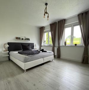 una camera bianca con un letto e due finestre di NEU Familienfreundliche FeWo in Seennähe im Leipziger Süden a Markkleeberg