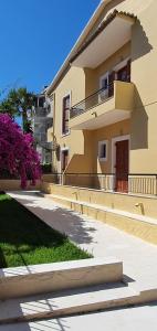 a large yellow house with purple flowers in front of it at Nicoll Apartments in Acharavi