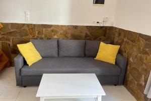 a couch with two yellow pillows in a living room at PANOS ROOMS Central loft studio near the beach in Andros
