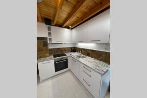 een keuken met witte kasten en een fornuis met oven bij PANOS ROOMS Beachfront apartment with Loft in Ándros