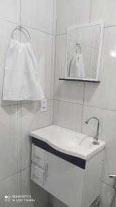 a white bathroom with a sink and a mirror at Pousada Quarto com ar, wi fi,frigobar perto da basilica in Aparecida