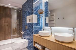 a bathroom with two sinks and a toilet and a shower at Best Western Hotel Jurata in Jurata