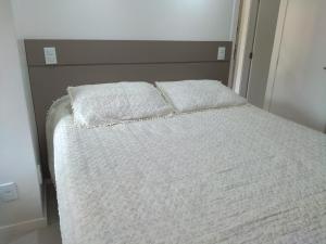 uma cama com duas almofadas num quarto em Mamelucos Chalé 11 Praia do Flamengo em Salvador