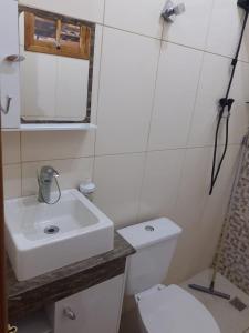 a bathroom with a sink and a toilet and a mirror at Cantinho do Sossego I in Serra Negra