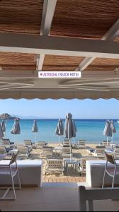 a beach area with chairs, tables and umbrellas at Acrogiali Beach Hotel Mykonos in Platis Gialos