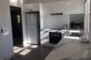 a kitchen with white cabinets and a black and white refrigerator at The Hermitage in Cooma