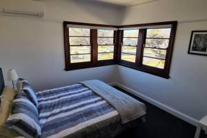 ein Schlafzimmer mit einem Bett und zwei Fenstern in der Unterkunft The Hermitage in Cooma