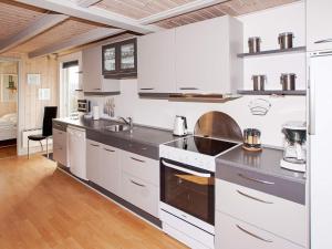 a large kitchen with white cabinets and appliances at 6 person holiday home in Hemmet in Falen