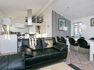 ein Wohnzimmer mit einem schwarzen Ledersofa und einer Küche in der Unterkunft 6 person holiday home in L kken in Løkken