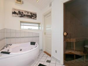 ein weißes Bad mit einer Badewanne und einer Dusche in der Unterkunft 6 person holiday home in L kken in Løkken