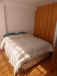 1 cama en un dormitorio con armario de madera en Apartamento Familiar Cusco, en Cusco