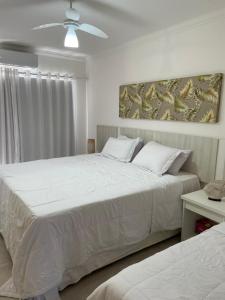 um quarto com 2 camas e uma ventoinha de tecto em Casa em condomínio fechado-Arraial D'ajuda-Alto da Pitinga em Arraial d'Ajuda