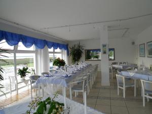 une salle à manger avec des tables et des chaises blanches dans l'établissement Rezydencja Nad Jeziorem Łebsko, à Łeba