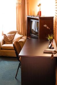 ein Wohnzimmer mit einem Sofa und einem Schreibtisch mit einem TV in der Unterkunft La Casa de Mamá Coyita in Cartago