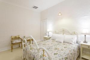 a white bedroom with a bed and two night stands at Ivanhoe Park Homestead in Tamworth