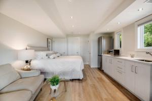 a large white bedroom with a bed and a couch at Sea-esta Suite with Ocean Views in Brentwood Bay in Brentwood Bay